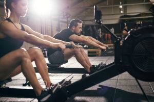 Woman and Man Rowing on Indoor Rowing Machines
