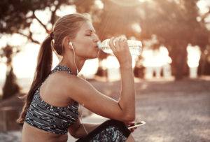 female in ponytail in spots bra drinking from water bottle