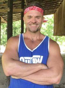 Brian Boyce - nutritionist and body builder, his profile picture with a blue muscle shirt and arms crossed in his barn