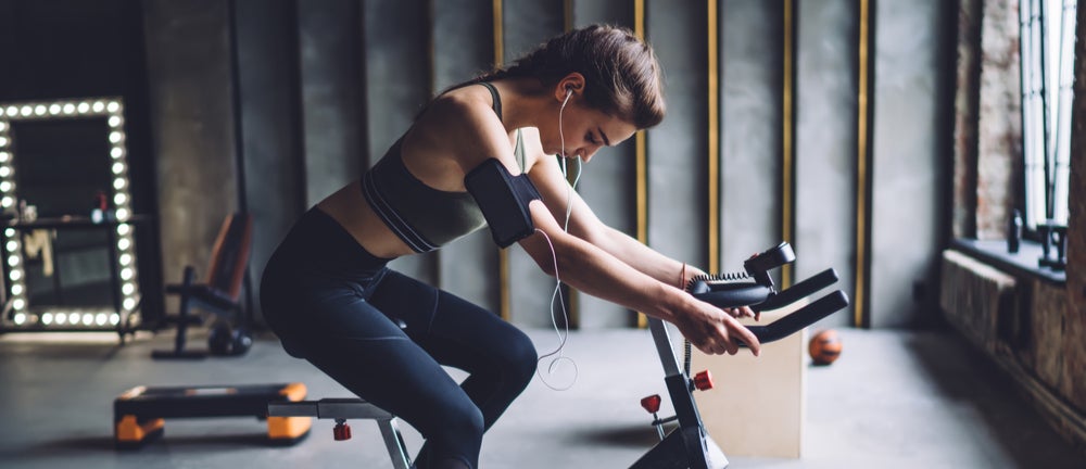 Girl listening to music and working out on spin bike