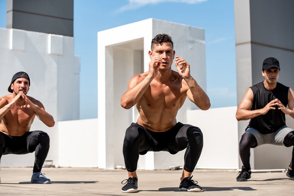 Group of Fit Sports Men Doing Squat Bodyweight Workout Training