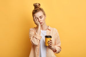 Tired woman holding a yellow cup of coffee