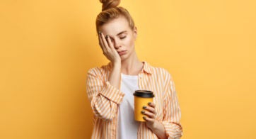 Tired woman holding a yellow cup of coffee
